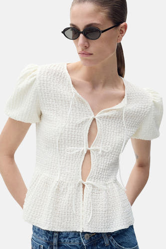 Blouse blanche à manches courtes de MANGO, avec un modèle peplum structuré et une matière texturée.