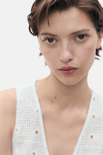 Blouse sans manches blanche de MANGO, avec des détails brodés et un motif raffiné.