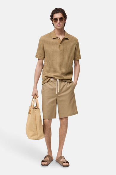 Beige court de MANGO, associé à une polo rayée, des sandales brunes et un sac tressé.