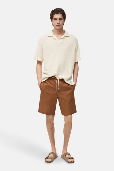 Short marron de MANGO, avec une ceinture et porté avec un polo beige et des sandales.