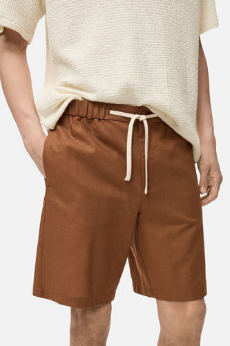 Short brun de MANGO avec cordon et poches, porté avec un t-shirt crème.