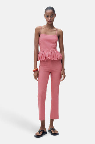 Blouse sans manches rouge de MANGO, avec un motif à carreaux gingham et une taille peplum, associée à une jupe et des sandales.