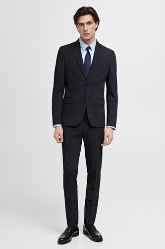 Blazer bleu de MANGO, porté avec une chemise bleu clair et une cravate bleu marine, avec des chaussures noires.