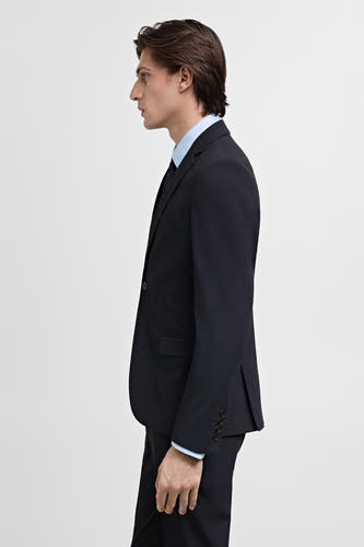 Blazer bleue de MANGO, affichée sur le côté, combinée avec une chemise bleu clair et une cravate bleu foncé.