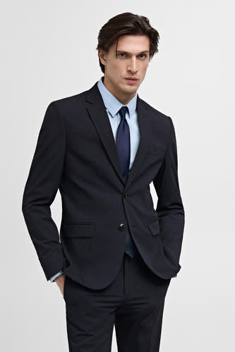 Blazer bleu de MANGO, avec une chemise bleu clair et une cravate bleu foncé.