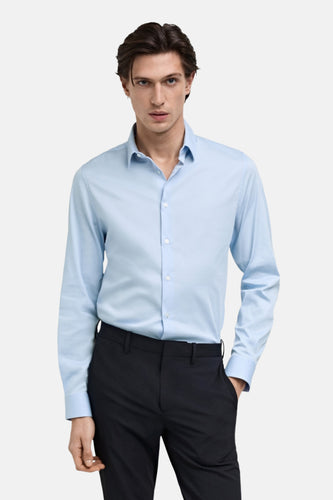 Blauw overhemd met lange mouwen van MANGO, gedragen met een donkere pantalon.