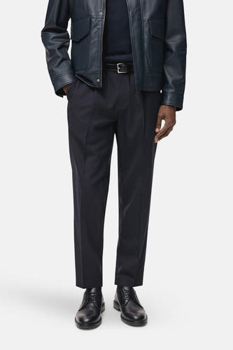 Pantalon de costume bleu MANGO, vu vu l'arrière, avec une veste en cuir bleu foncé.