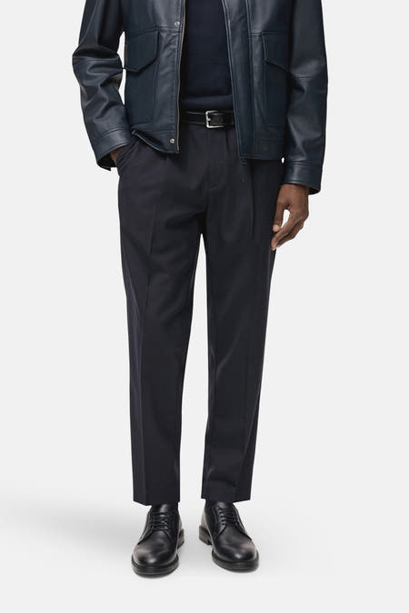 Pantalon de costume bleu MANGO, vu vu l'arrière, avec une veste en cuir bleu foncé.