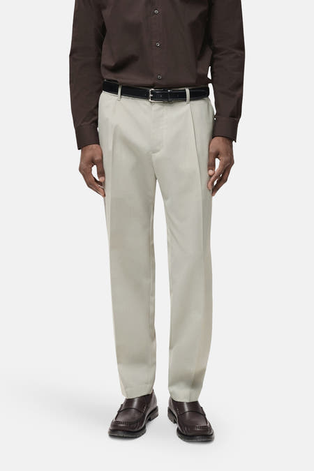 Pantalon gris de MANGO, à plis et avec une ceinture noire, associé à un chemise marron et des chaussures marrons.