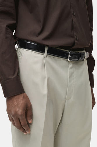 Pantalon de costume gris MANGO, avec plis et une ceinture noire autour de la taille.