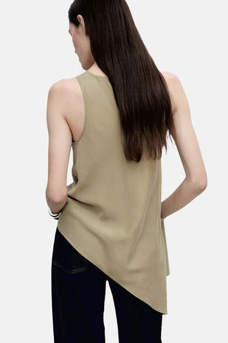 Blouse sans manches kaki MANGO, coupée de manière asymétrique avec une texture lisse, associée à un pantalon foncé.