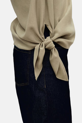 Blouse kaki de MANGO, boutonnée sur le côté sur un pantalon denim bleu marine.