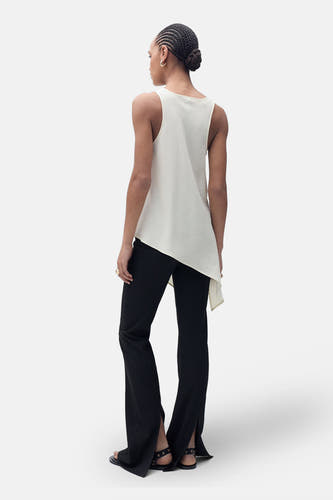 Blouse sans manches de MANGO, portée avec une jupe asymétrique noire et des sandales.