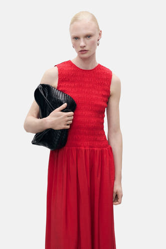 Jupe sans manches rouge de MANGO, avec des détails plissés sur le corps et une poche main tressée noire.