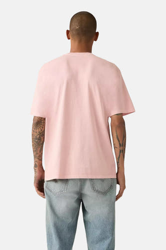 T-shirt rose à manches courtes de Levi's, avec des tatouages sur les deux bras et un jean bleu.