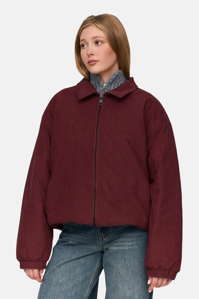 Veste rouge de 24 colours GMBH, en tissu corduroy, avec une fermeture éclair et des jeans bleus.