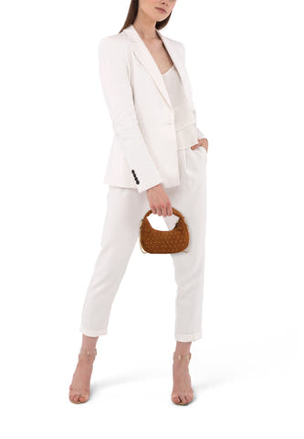 Sac à main beige aspect suède d'Access® avec clous dorés et détails chaîne, porté par un mannequin en tailleur blanc.
