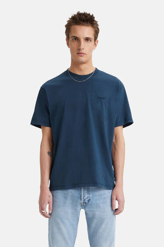 T-shirt bleu à manches courtes de Levi's®, avec un logo subtil sur la poitrine et porté avec une chaîne d'argent et des jeans.