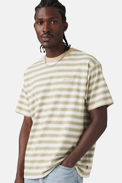 Een man met een gestreept Levi's T-shirt en een zilveren ketting.