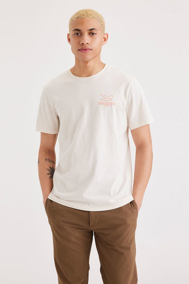 T-shirt blanc à manches courtes de DOCKERS, avec petit logo sur la poitrine, associé à un pantalon marron.