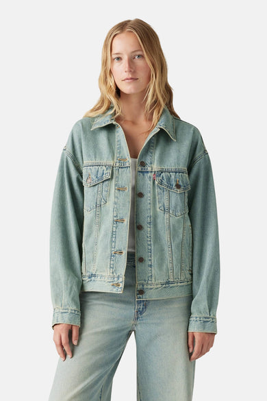 Vrouw met blauw denim jasje en broek.

