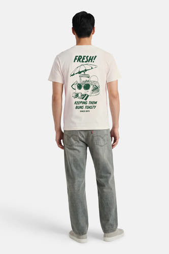T-shirt beige à manches courtes de Levi's® avec un imprimé graphique au dos, associé à un jean gris.