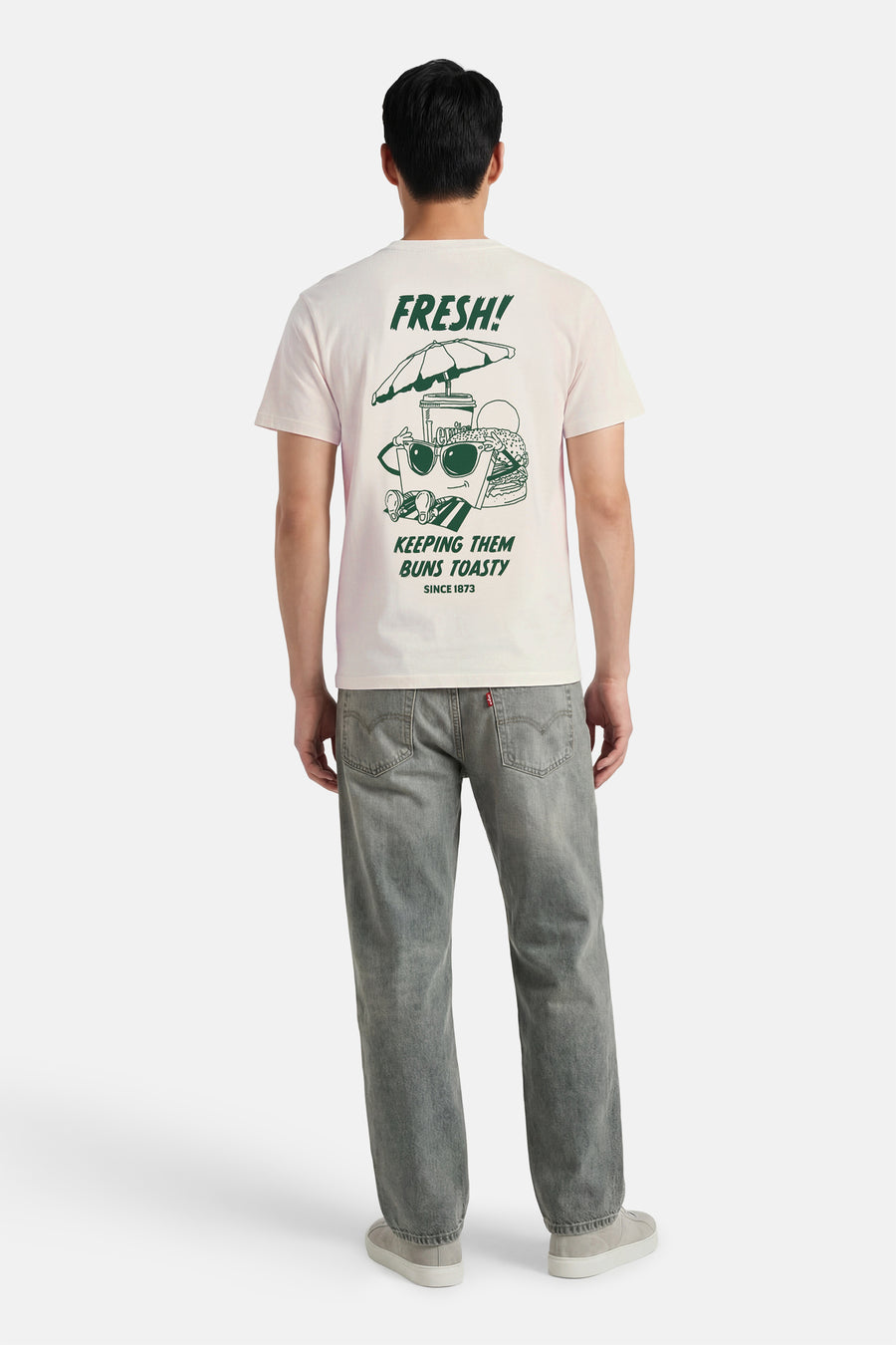 T-shirt beige à manches courtes de Levi's® avec un imprimé graphique au dos, associé à un jean gris.