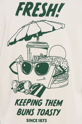 T-shirt beige à manches courtes de Levi's®, avec motif de dessin animé vert représentant de la nourriture et du texte.