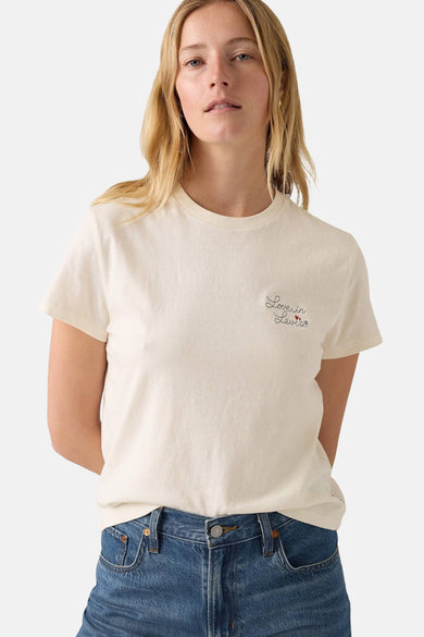 T-shirt écru à manches courtes de Levi's, avec un petit texte et porté avec un jean bleu.
