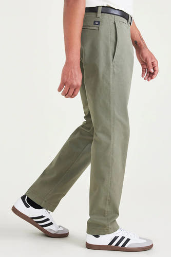 Chino vert de DOCKERS, avec une ceinture noire et des baskets blanches à rayures noires en vue latérale.