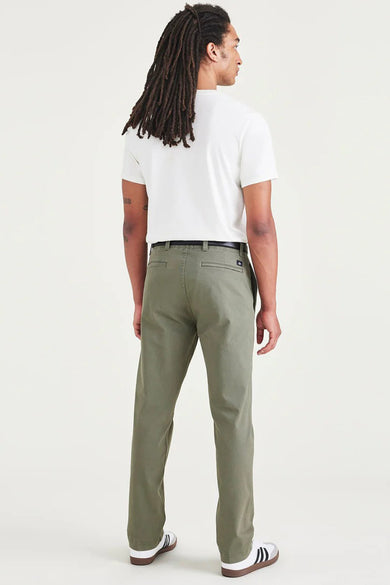 Groene chino van DOCKERS, achterkant, met een zwarte riem, gecombineerd met een wit T-shirt en sneakers.
