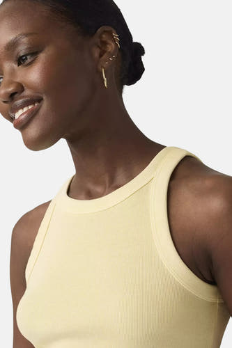 Haut jaune de Levi's, sans manches avec encolure ronde et texture côtelée, portée avec des boucles d'oreilles dorées.