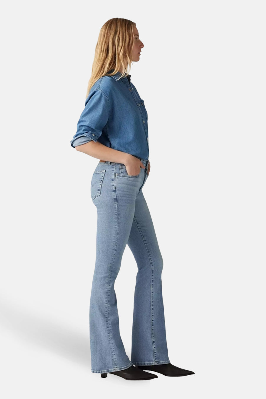 Jeans flared lichtblauwe denim van Levi's, met een spijkerblouse en zwarte schoenen, in zijaanzicht.
