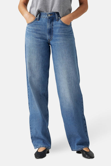 Jean droit en denim bleu moyen de Levi's®, avec patch en cuir iconique et détails de poche arrière visibles.