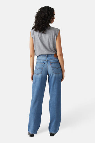 Jean droit bleu denim mi-mollet de Levi's, vu de derrière, avec une chemise grise et des chaussures noires.