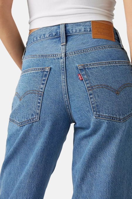 Blauw spijkerbroek met bruin en rood logo.
