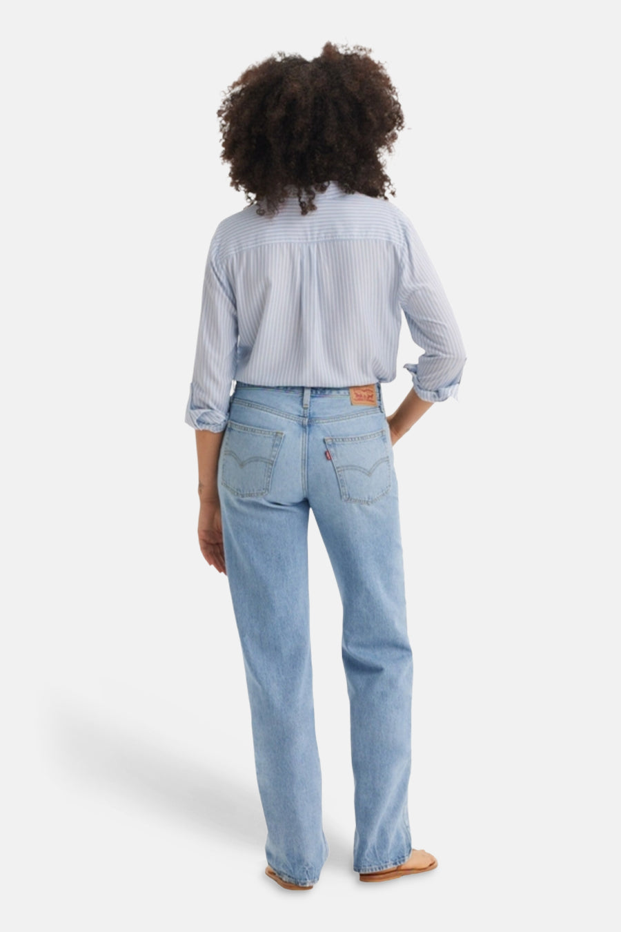 Jean droit bleu clair de Levi's, avec un patch rouge et porté avec une chemise rayée.