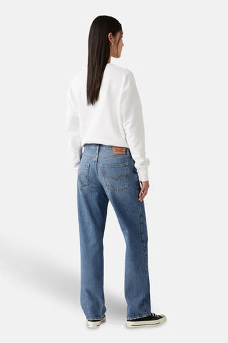 Jean droit en denim bleu clair de Levi's, vu de l'arrière, combiné avec un sweat-shirt blanc et des baskets noires.