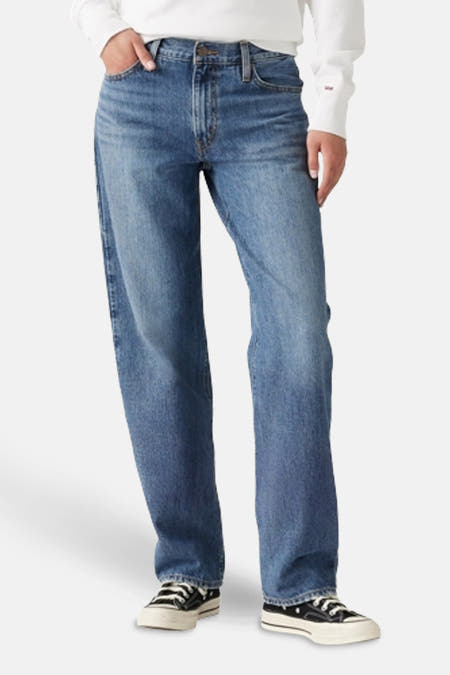 Jean droit en denim bleu clair de Levi's, avec des points visibles, porté avec des baskets noires et un t-shirt blanc.