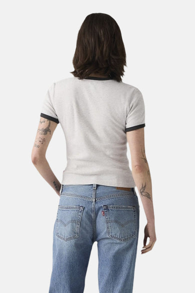T-shirt beige à manches courtes de Levi's, avec des bordures noires et porté avec un jeans bleu.