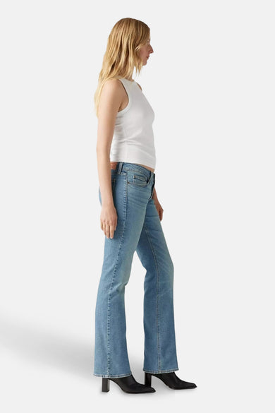 Jean bootcut bleu clair de Levi's, porté avec un t-shirt blanc et des bottes noires à talon, en vue latérale.