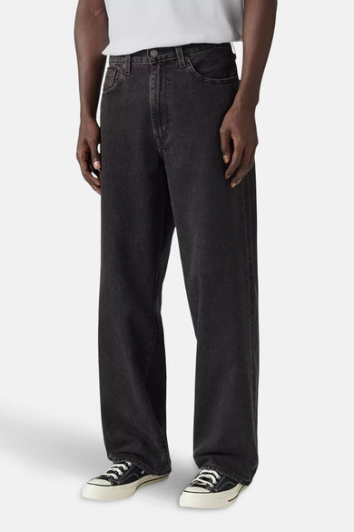 Jean décontracté de denim gris foncé de Levi's®, associé à des baskets blanches et un t-shirt blanc.
