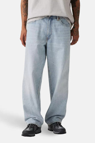 Jean en denim bleu clair large de Levi's®, avec une coupe décontractée et des chaussures noires.