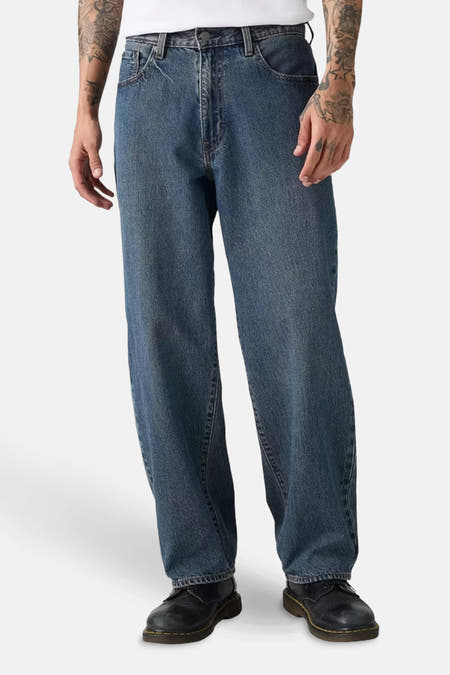 Jean droit en denim bleu-noir de Levi's®, avec une coupe décontractée et des chaussures Dr. Martens.