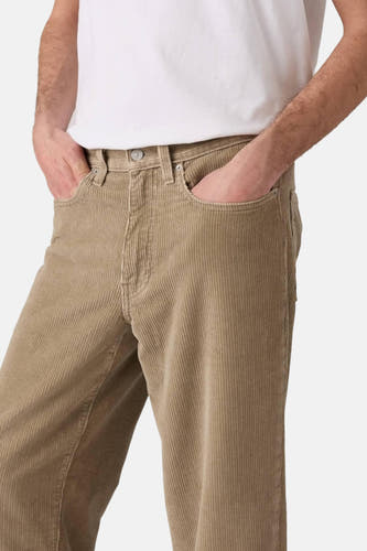 Beige corduroy broek van Levi's, met steekzakken en een rechte pijp, gedragen met een wit T-shirt.
