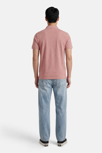 Polo rose Levi's® à manches courtes, dos visible, combinée avec un jean bleu clair et des baskets noires.