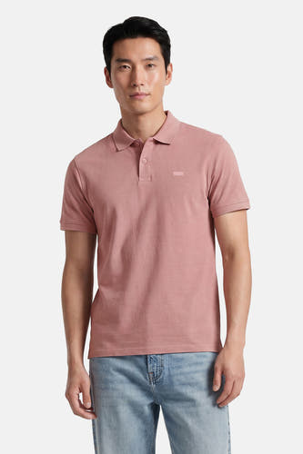 Polo rose Levi's® à manches courtes avec un logo discret sur la poitrine, porté par un homme avec un jean clair.