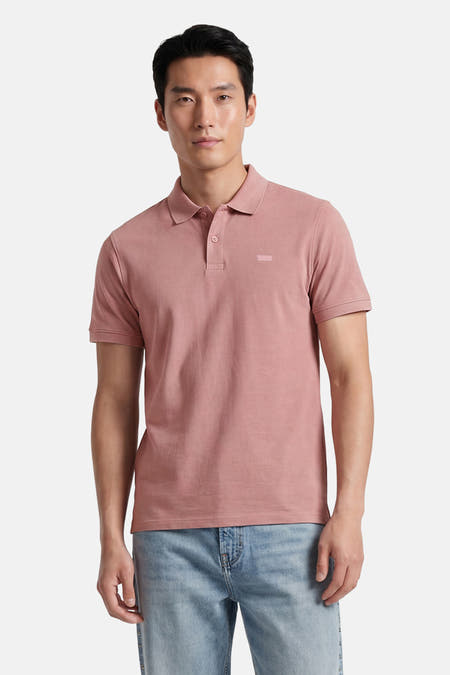Polo rose Levi's® à manches courtes avec un logo discret sur la poitrine, porté par un homme avec un jean clair.
