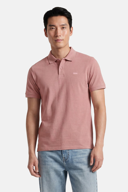 Polo rose Levi's® à manches courtes avec un logo discret sur la poitrine, porté par un homme avec un jean clair.