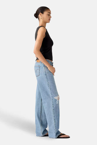 Jeans wide van blauw denim van Levi's®, met een gescheurde knie, gecombineerd met een zwarte tanktop.